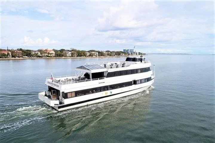 A white multi-deck cruise boat on Charleston Harbor