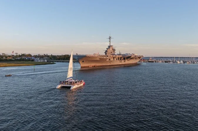 A catamaran sailing past the USS Yorktown aircraft carrier in Charleston Harbor